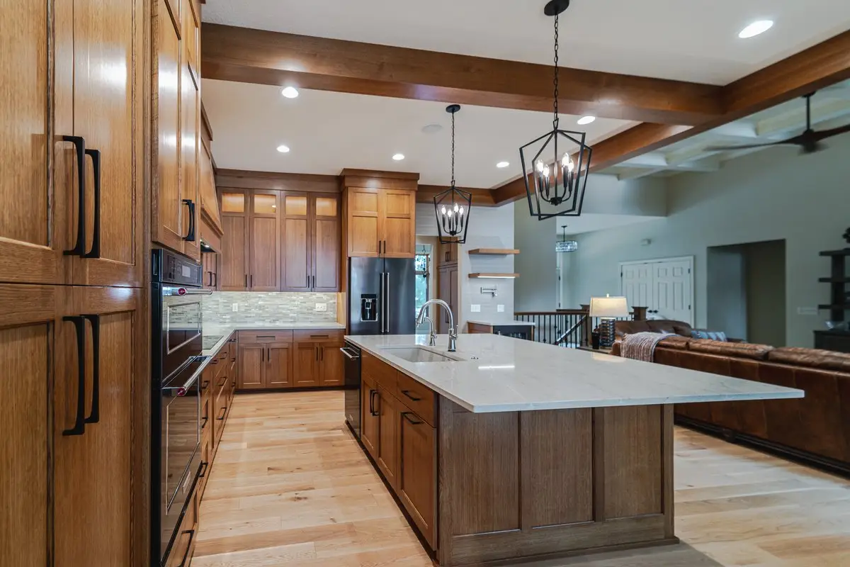 Modern kitchen with wood cabinetry, stainless steel appliances, and a large white island with a double sink.