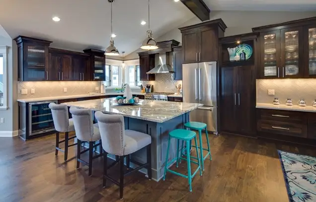 Modern kitchen with dark wood cabinets, stainless steel appliances, and a marble island with five bar stools.